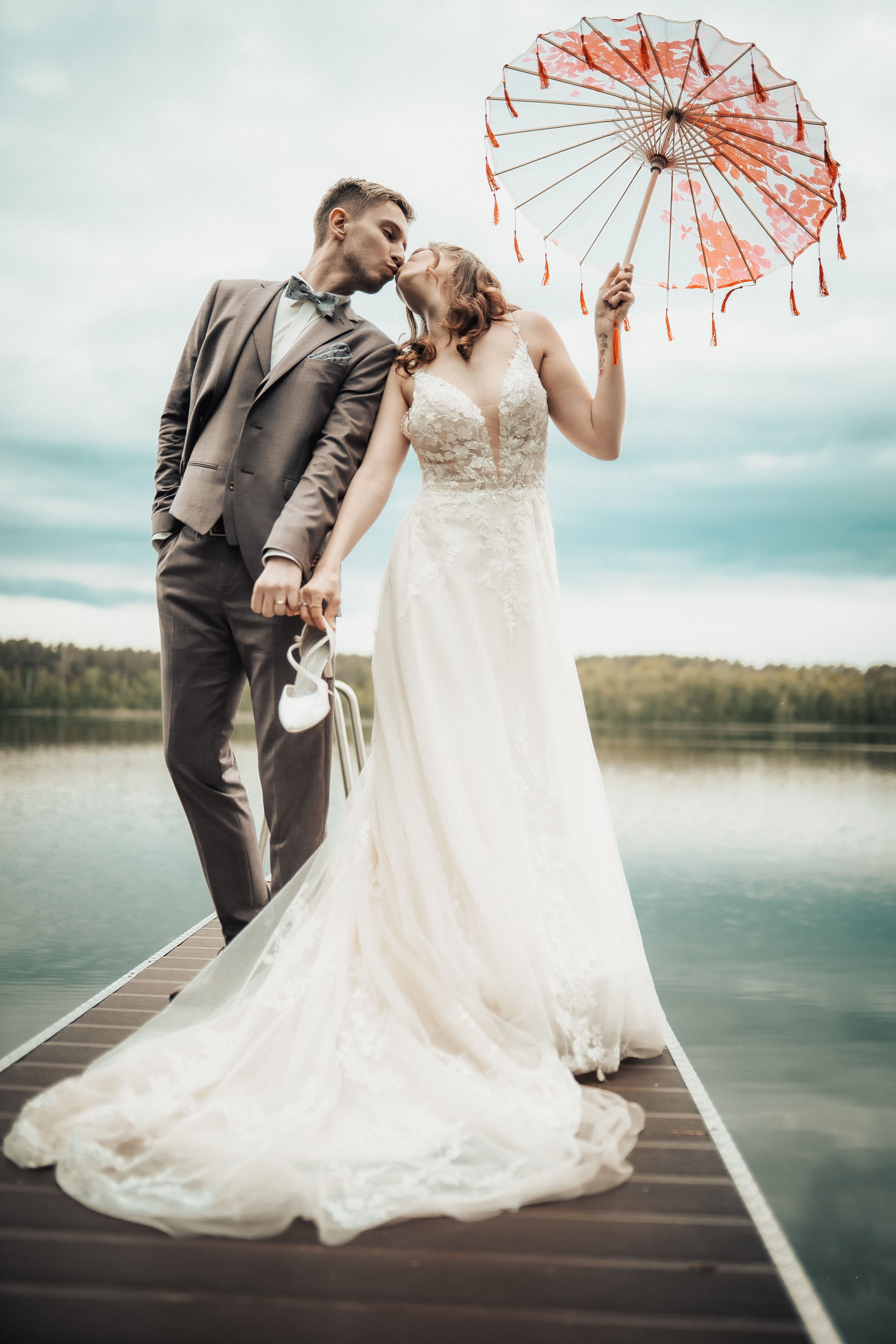 Hochzeitspaar am See mit dekorativem Sonnenschirm