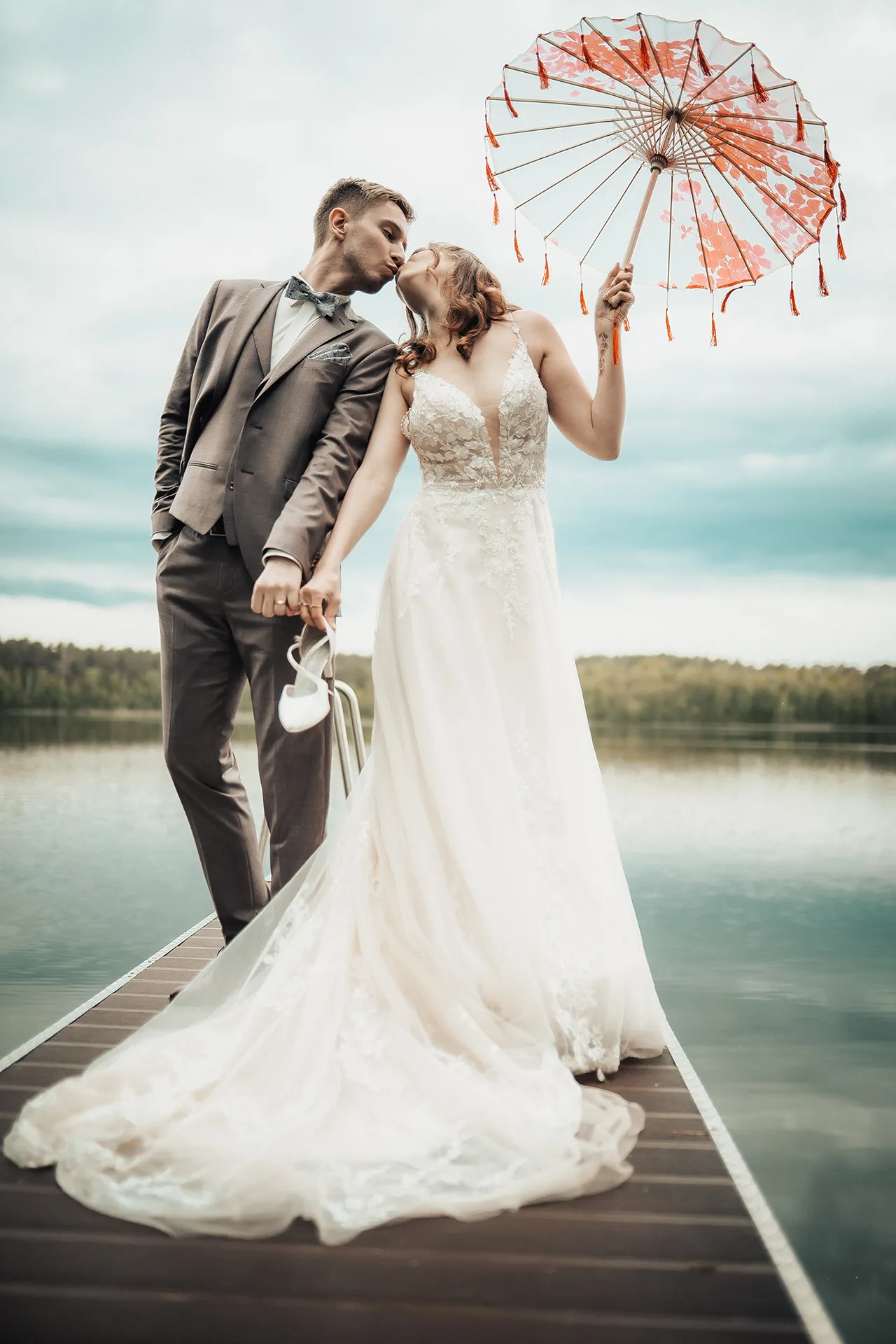 Hochzeitspaar am See mit dekorativem Sonnenschirm