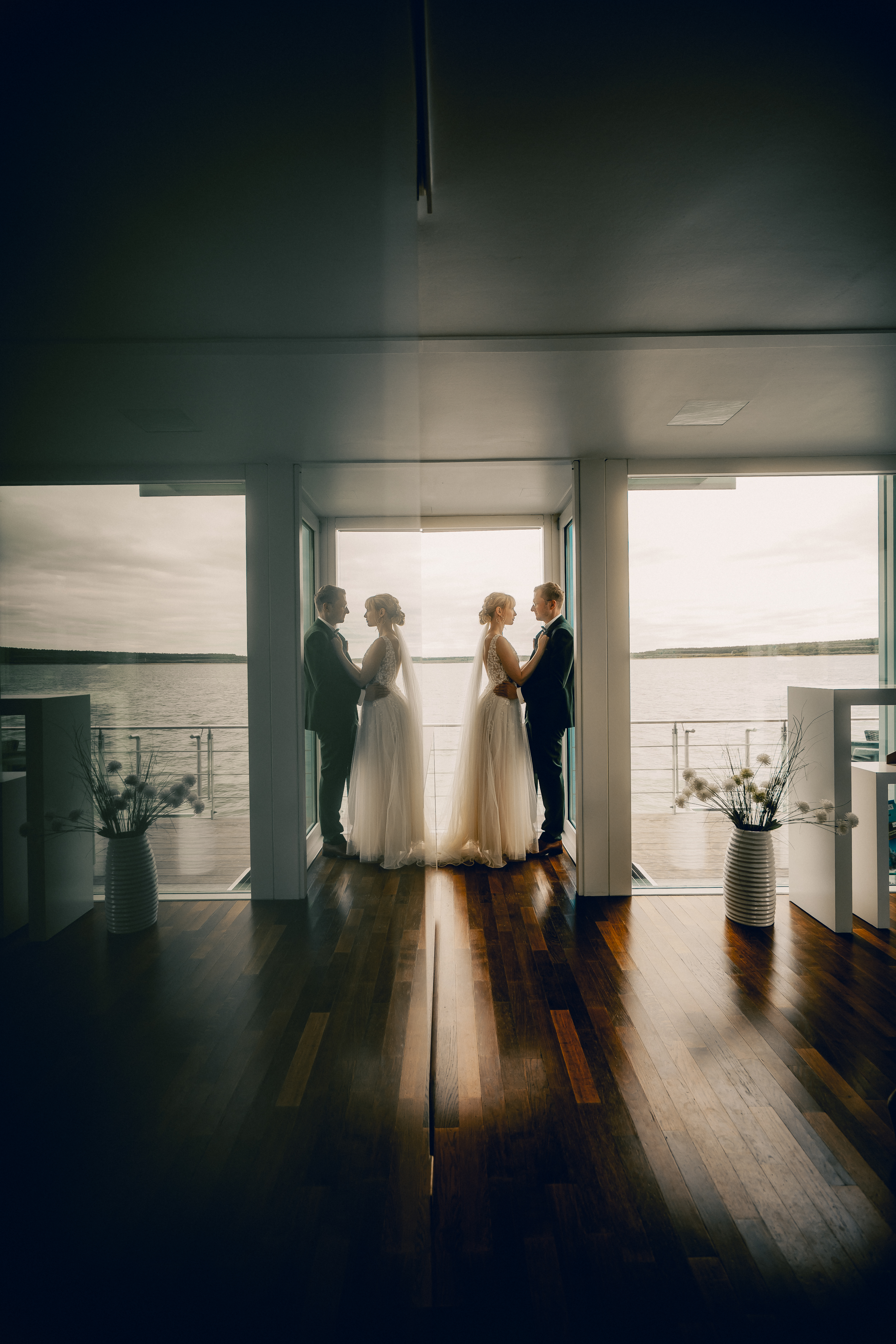 Hochzeitspaar vor einer Fensterfront am Wasser