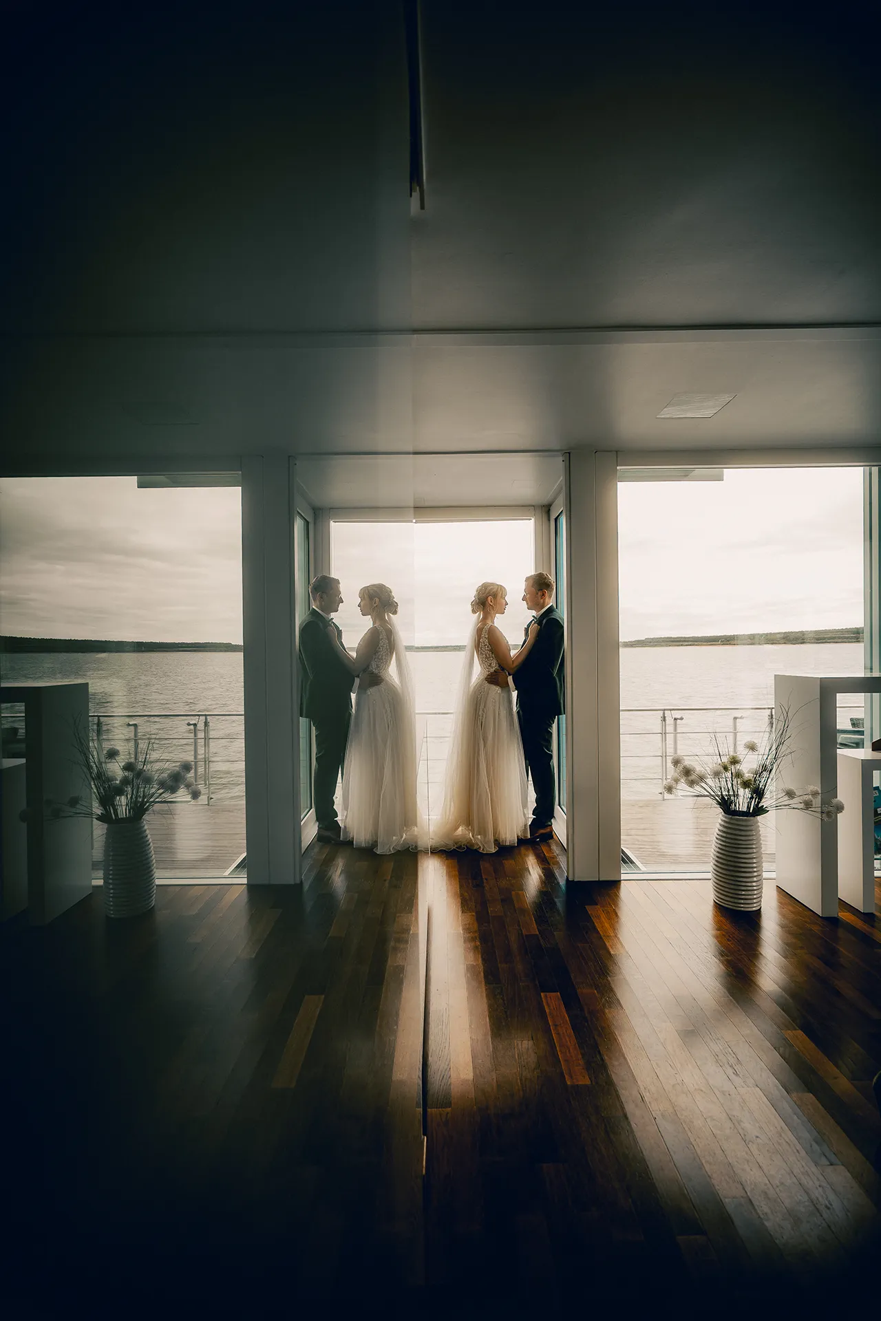 Hochzeitspaar vor einer Fensterfront am Wasser